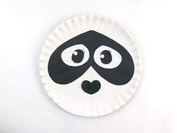 Paper plate with assembled panda eyes, mask, and nose.