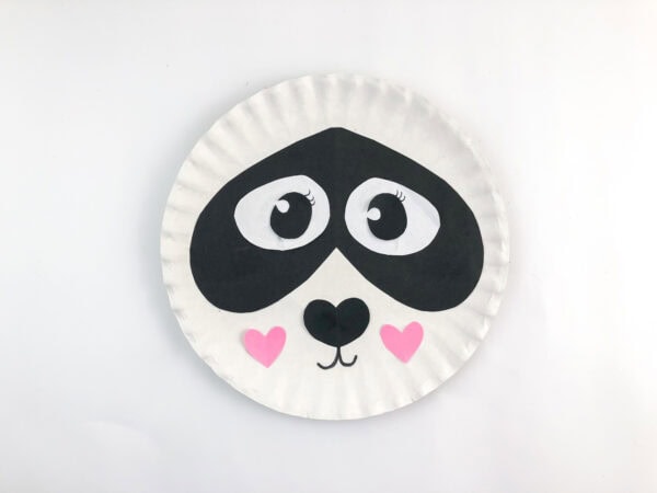 Paper plate panda face with heart cheeks.
