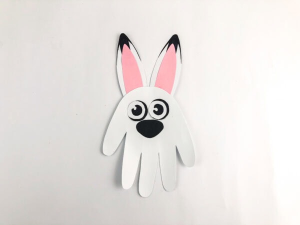 Paper handprint hare with ears, eyes, and nose glued on.