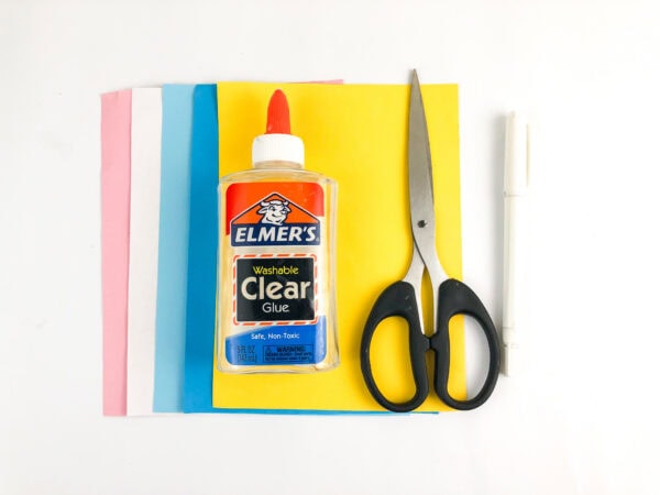 Craft supplies including colored paper, glue, scissors, and a marker.