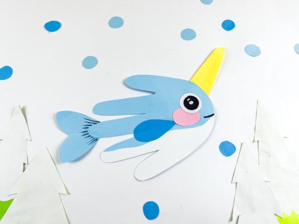 Finished narwhal craft displayed with blue paper dots and trees.