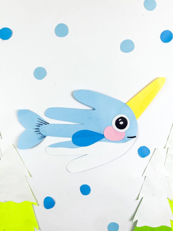 Paper narwhal handprint craft with blue dots and paper trees.