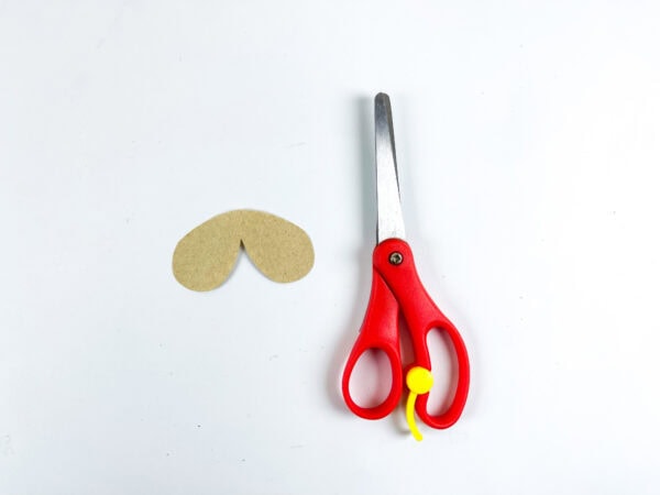 Cutout beige snout piece next to scissors.