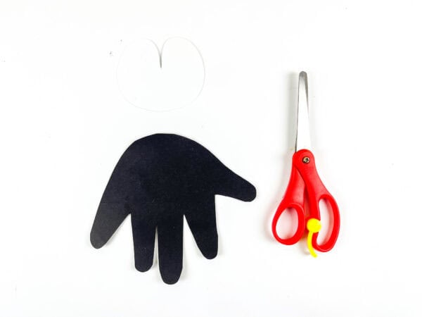 Black handprint cutout and scissors on white background.