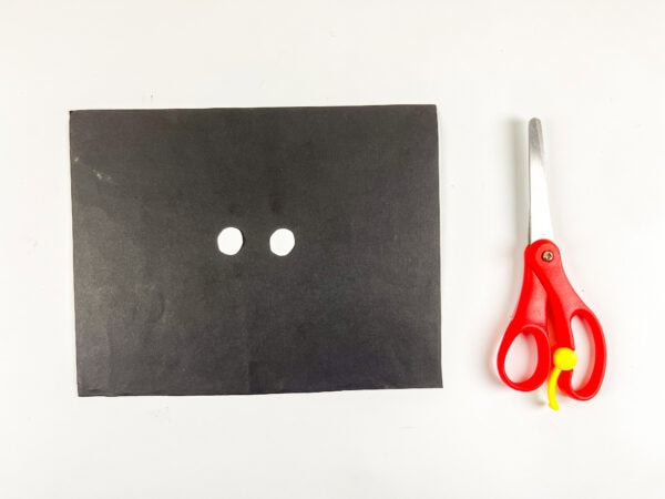 Black paper with two small white circles and scissors.