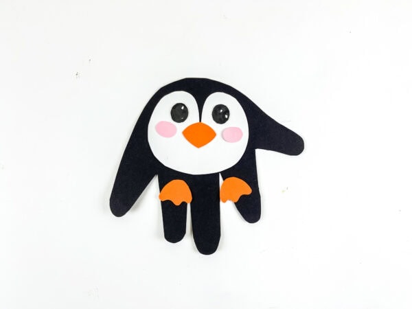 Finished penguin handprint craft on a white background.