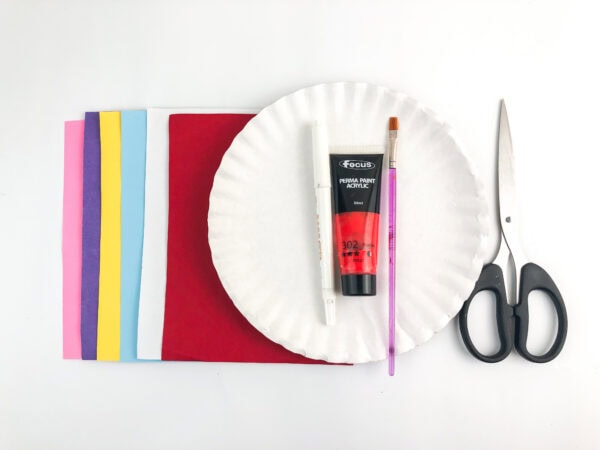 Craft materials including paper, paint, brush, scissors, and paper plate.