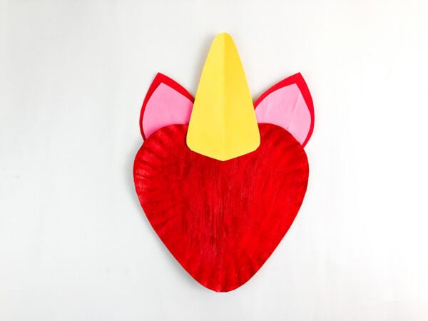 Red unicorn paper plate base with ears and yellow horn attached.