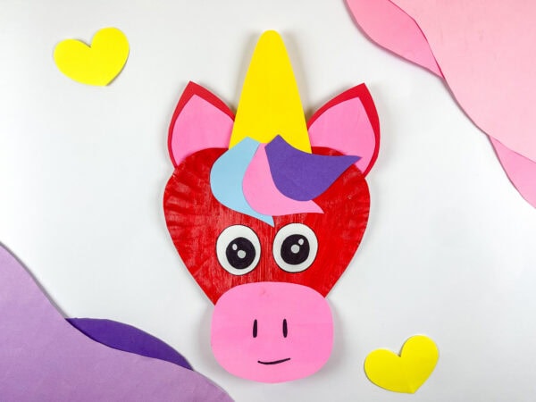 Finished unicorn paper plate craft displayed with yellow hearts.