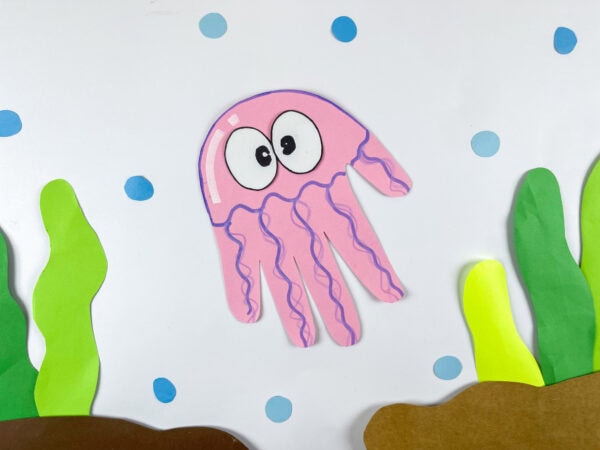 Jellyfish handprint craft in an underwater scene with paper sea plants
