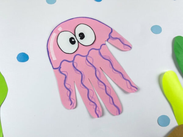 Jellyfish handprint craft placed in an ocean-themed background