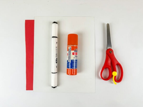Craft supplies with red paper, glue stick, marker, and scissors