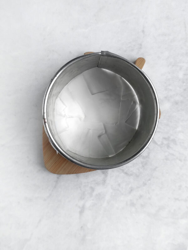 Round mold lined with parchment paper viewed from above.