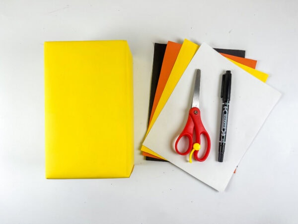 Yellow paper, colored paper, scissors, and marker supplies