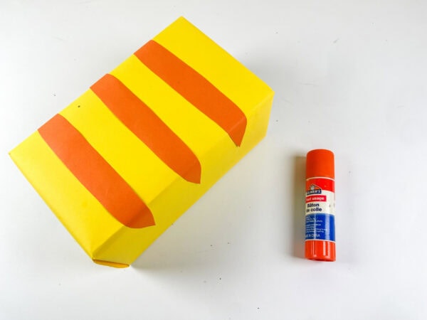 Yellow box with orange stripes and glue stick