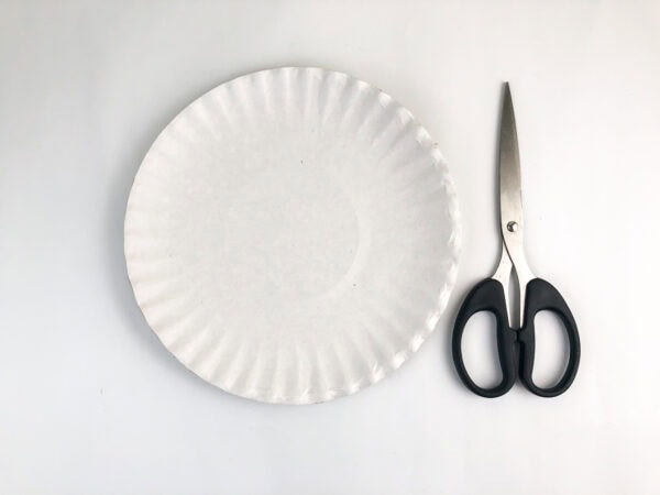 White paper plate and scissors on table