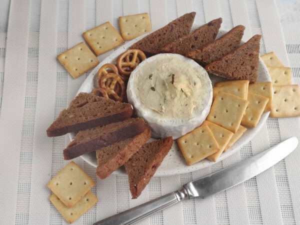 Finished brie candle board with bread, crackers, and pretzels arranged around it.