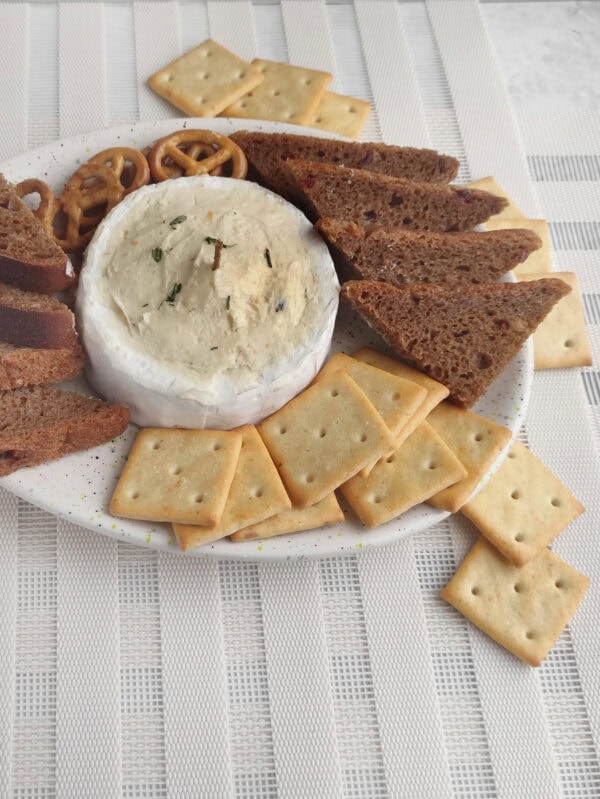 Brie candle board served on a white plate with crackers and bread.