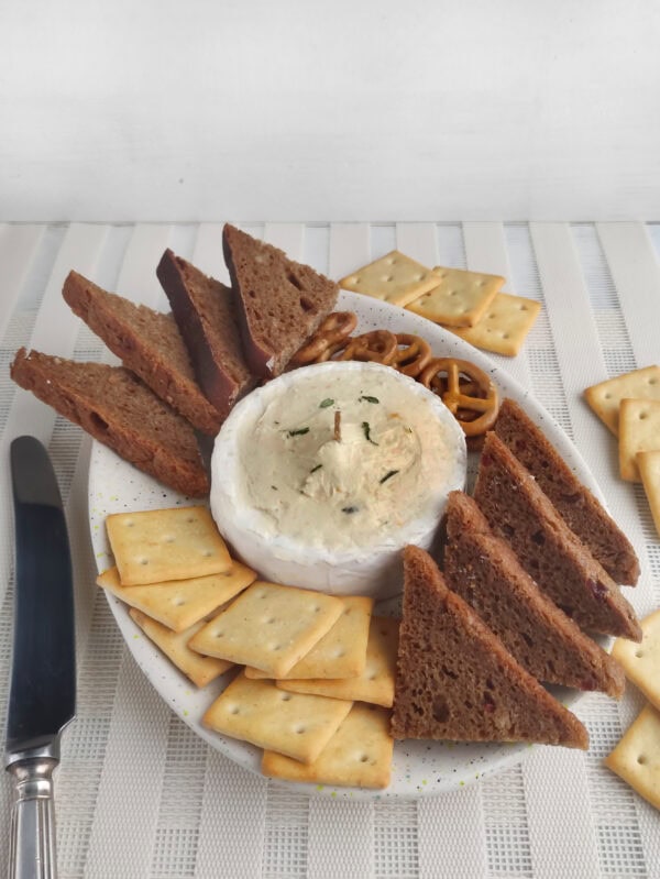 Side view of brie candle board with knife, bread slices, and crackers.

