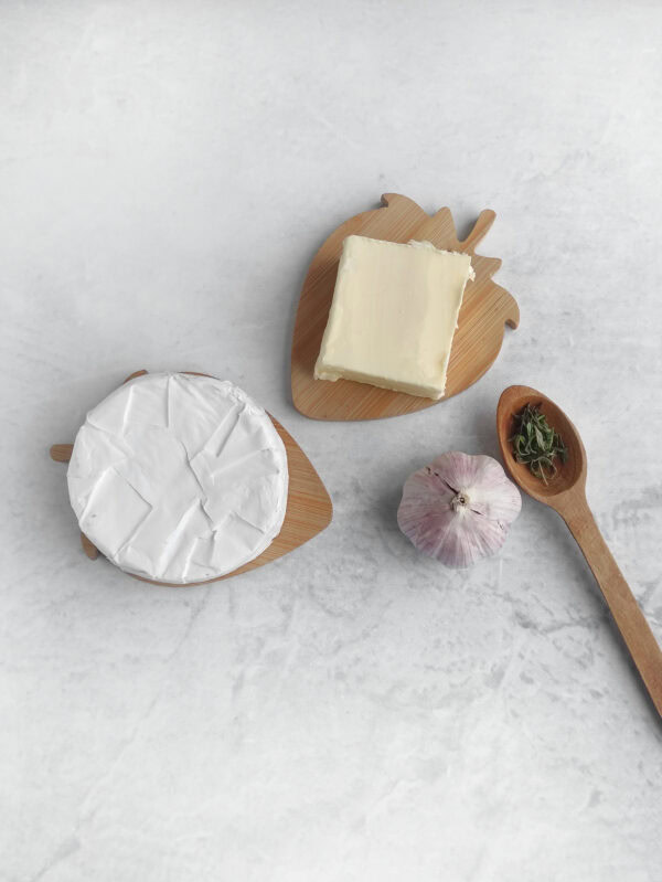 Brie wheel, butter, garlic, and herbs arranged on a countertop.