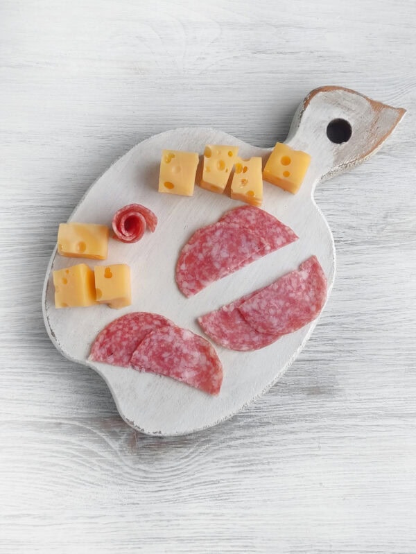 Salami slices and cheese cubes arranged to prepare hedgehog spikes and decorations