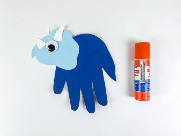 Head and horns attached to blue handprint body with glue stick beside it