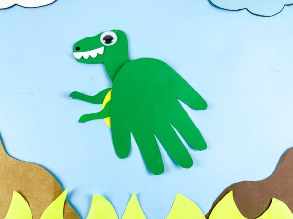 Green Tyrannosaurus handprint craft above paper grass