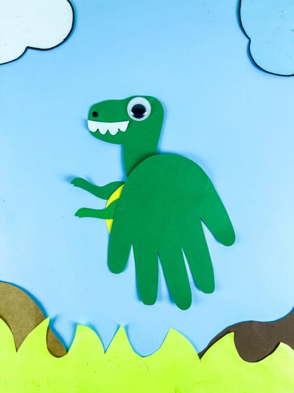 Green Tyrannosaurus handprint craft with grass and clouds