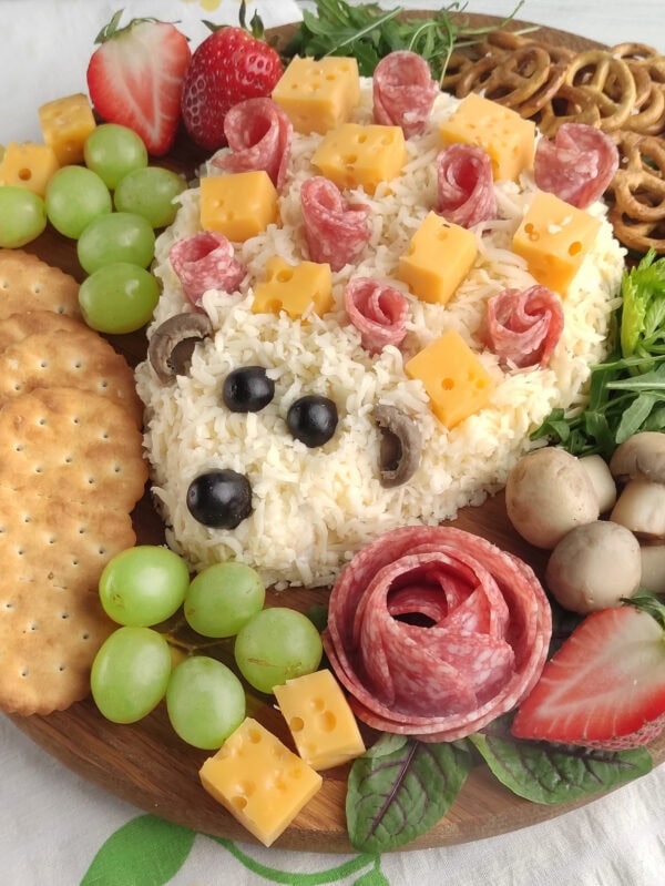 Close-up of finished hedgehog charcuterie board with salami roses, cheese cubes, grapes, and crackers