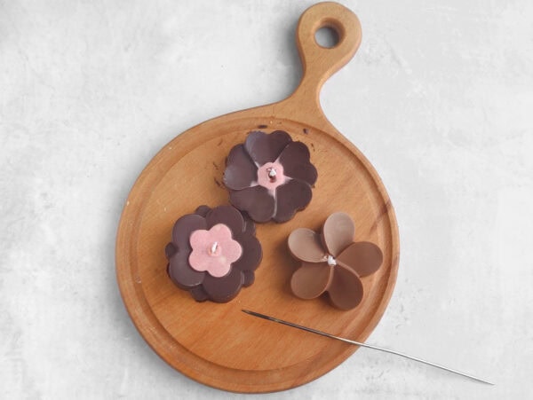 Chocolate flower candles with wicks on wooden board