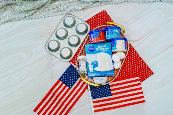 Cupcake ingredients with pan, frosting, and flags