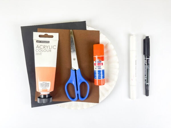 Craft supplies with paper plate, paint, scissors, glue, and markers