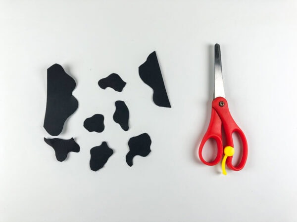 Black paper cow spots cut beside scissors