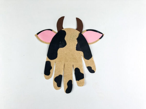 Cow handprint craft with ears horns and spots attached