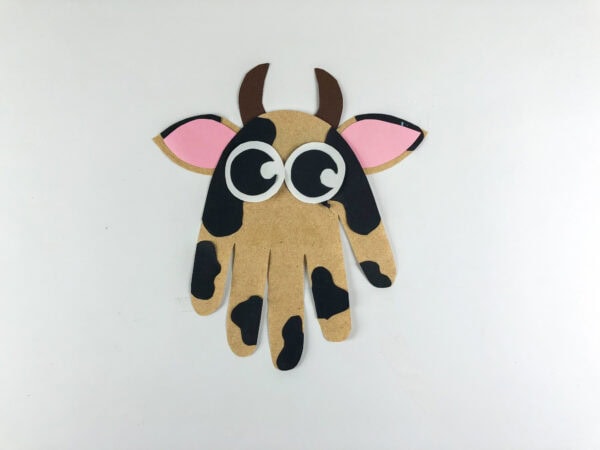 Completed cow handprint craft with eyes nose horns and ears attached