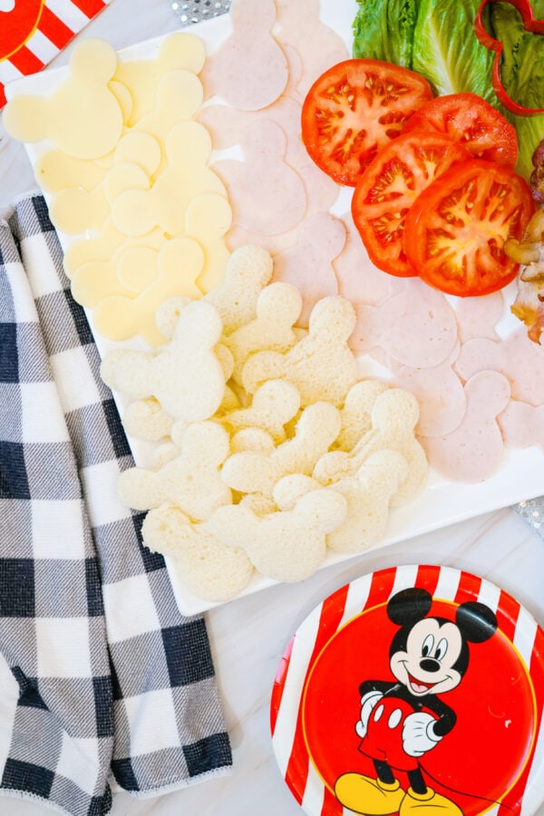 Mickey-shaped bread, cheese, and turkey slices with tomatoes on platter