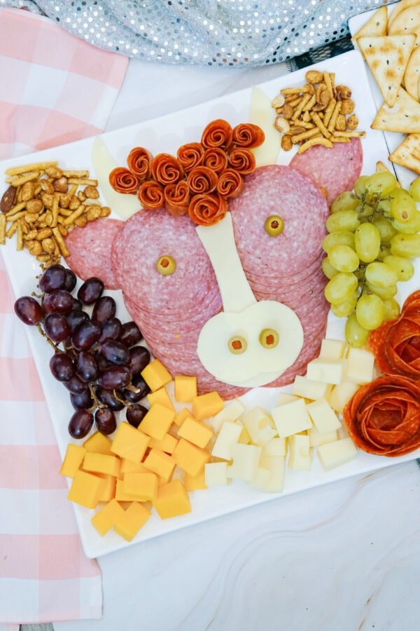 Highland cow themed charcuterie board with cheese, grapes, and salami