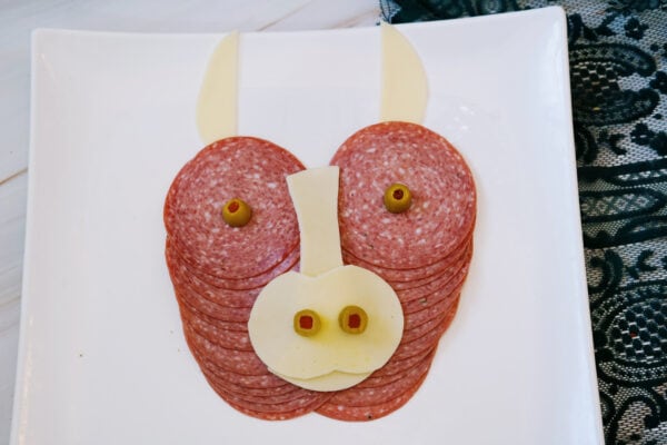 Highland cow charcuterie board with olive eyes and cheese nose