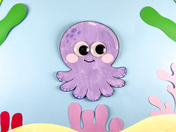 paper plate octopus craft on ocean paper background.