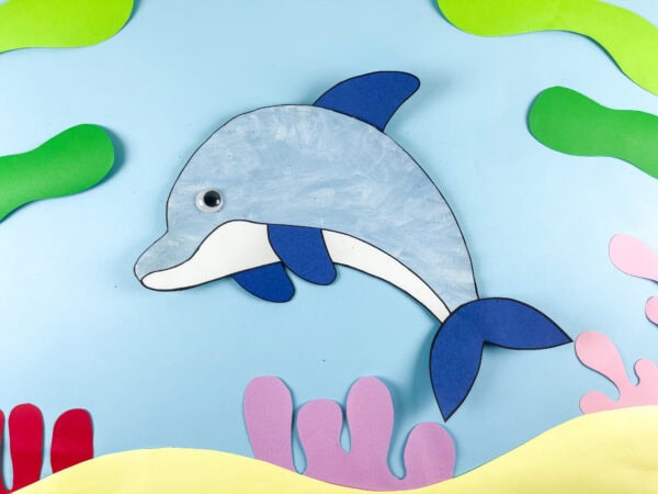 Paper plate dolphin craft on ocean background