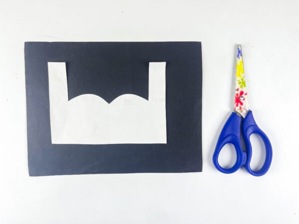 Black paper cutout with mustache shape and scissors