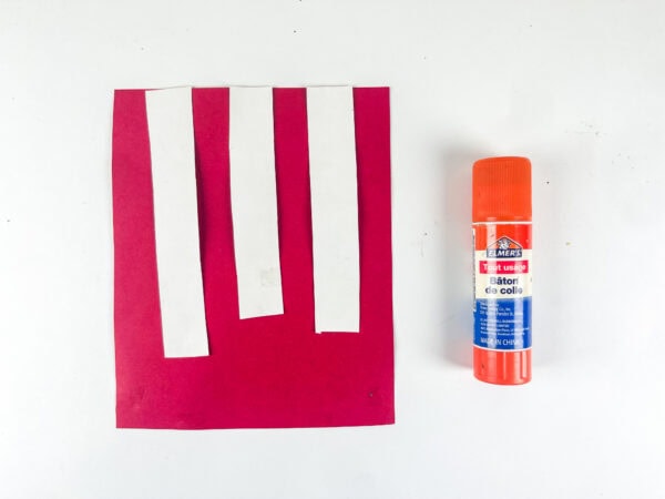Red paper with white strips and glue stick
