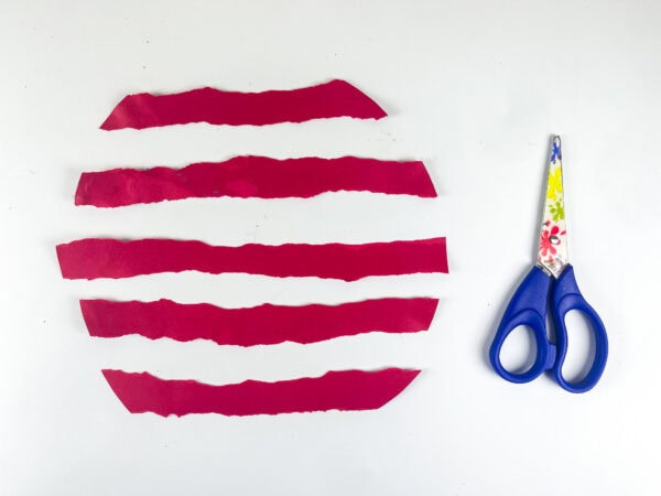 Red paper strips on paper plate with scissors