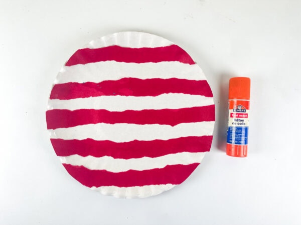 Paper plate with red flag lines and glue stick
