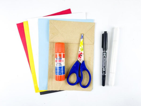 Colored paper, glue stick, scissors, and markers for school bus craft