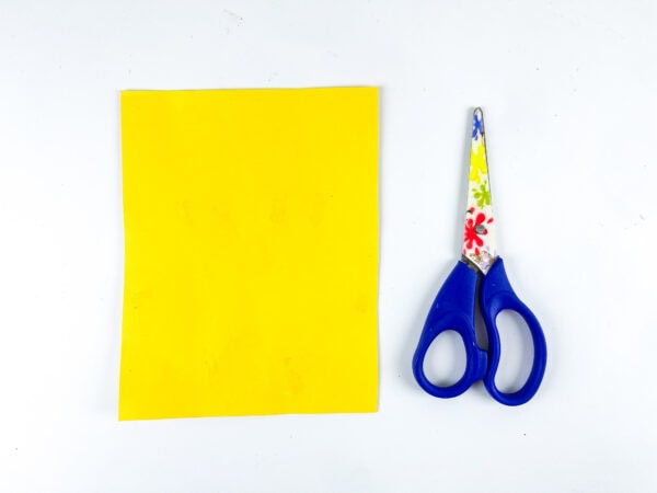 Yellow paper sheet and scissors for school bus craft