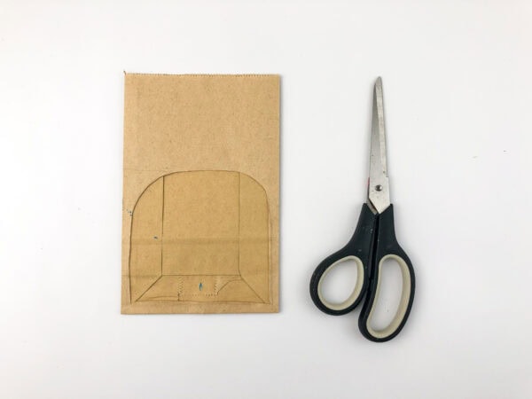 Paper bag with a cave archway outline drawn on it, next to scissors.
