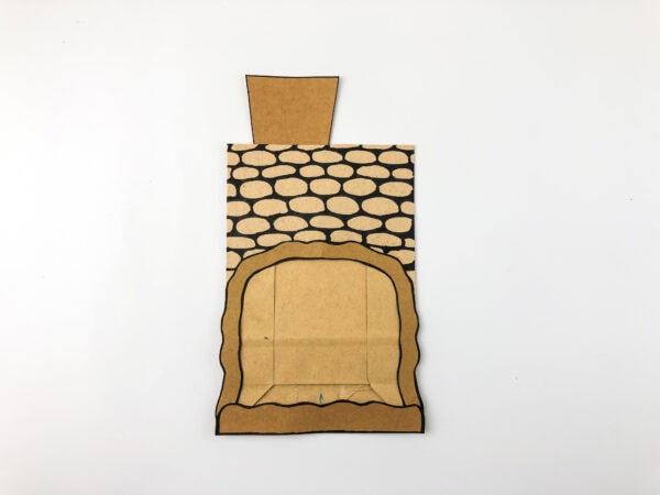 Assembled cave front piece with stone pattern and chimney shape attached to paper bag.