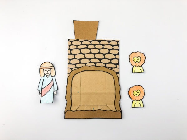 Colored Daniel and lion cutouts laid next to the assembled cave craft.