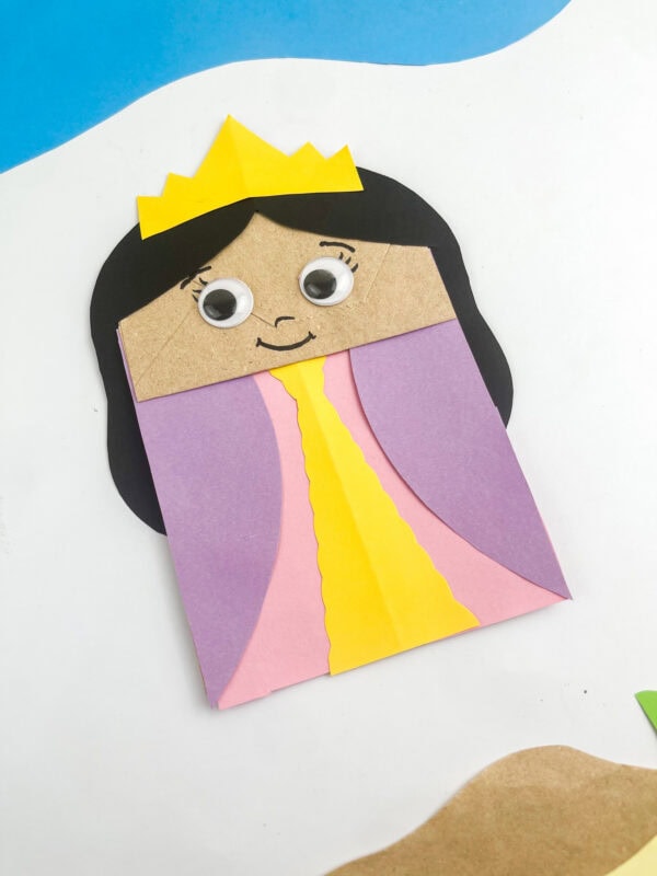 Finished Queen Esther paper bag puppet shown at an angle against a desert backdrop